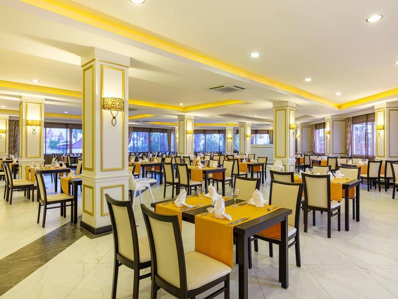 Restaurante de hotel luminoso y elegante con paredes amarillas y mesas y sillas bien dispuestas.