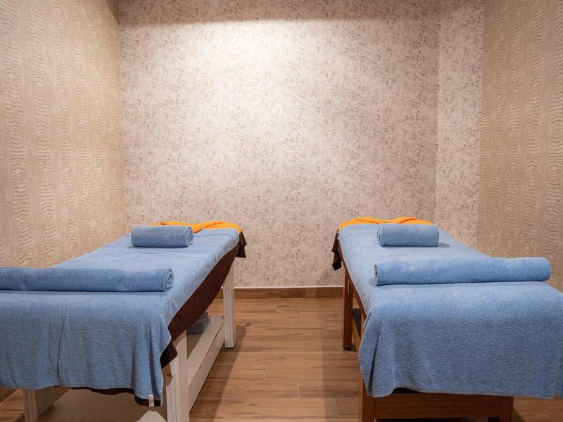 Dos camillas de masaje con mantas azules en una habitación tranquila con luz cálida.