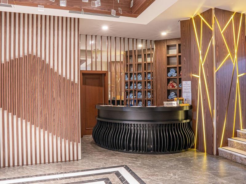 Lobby moderna de hotel con mostrador de recepción redondo negro y paneles de madera decorativos.