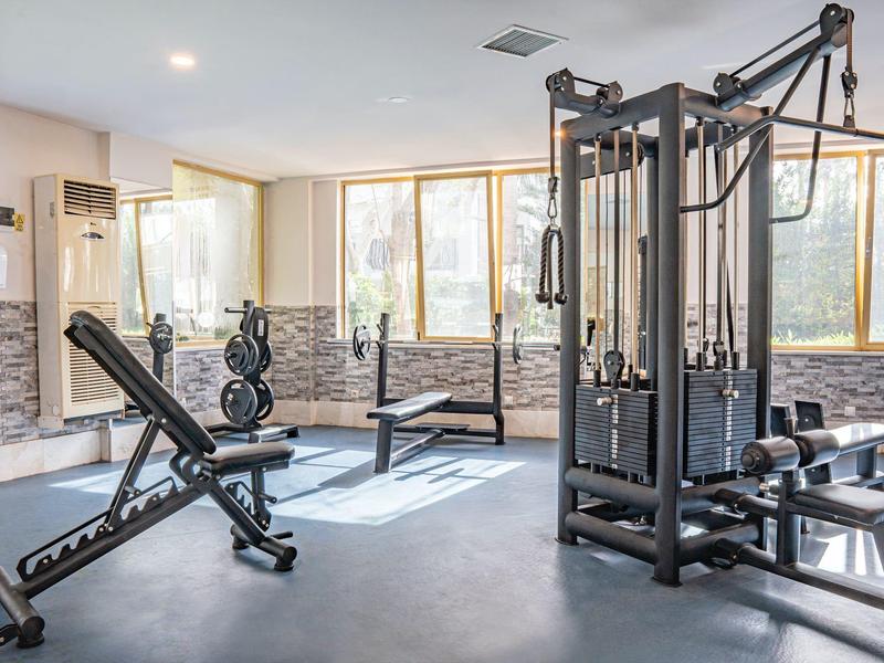 Gimnasio luminoso con equipos modernos y grandes ventanas en un hotel.
