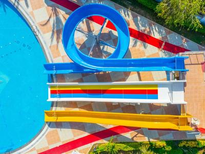 Zone de parc aquatique moderne avec toboggan bleu et piscine dans un complexe hôtelier.