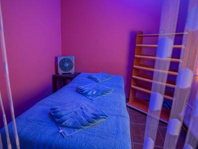 Une pièce calme éclairée en bleu avec une table de massage et des serviettes dans un cadre hôtelier.