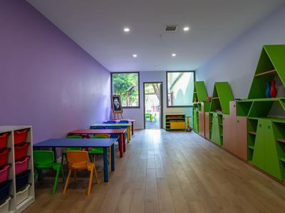 Salle de jeux lumineuse avec meubles colorés et étagères dans un hôtel ou une maison de vacances.