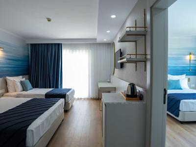 Chambre d'hôtel moderne avec deux lits, rideaux bleus et sol en bois.