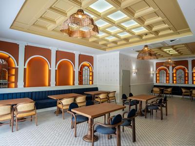 Espace de restauration d'hôtel élégant avec tables en bois, bancs rembourrés et lumière chaude.