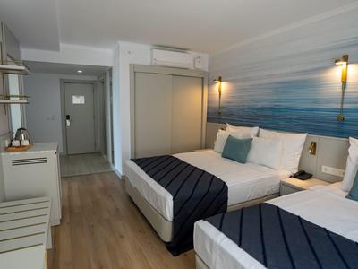 Chambre d'hôtel lumineuse avec deux lits doubles, décoration bleu-blanc et sol en bois.