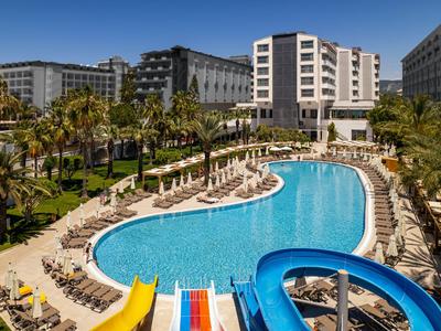Hotel z dużym basenem, zjeżdżalniami i leżakami w tropikalnym otoczeniu.