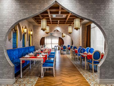Elegancka restauracja z niebiesko-czerwonymi krzesłami pod szarą ceglanym łukiem.