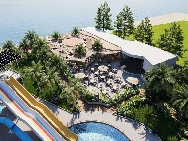 Área exterior de un resort con parque acuático, piscina, toboganes y zonas de descanso junto al mar.