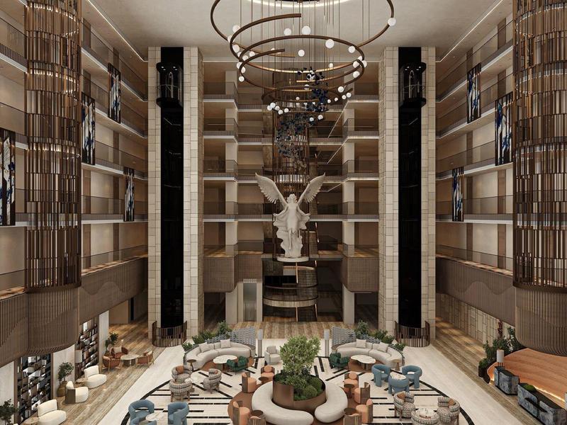 Amplio y lujoso vestíbulo de hotel con paredes altas, candelabros y estatua decorativa en el centro.