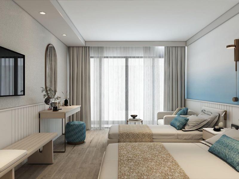 Habitación de hotel luminosa con dos camas, escritorio, televisor y ventana grande con cortinas.