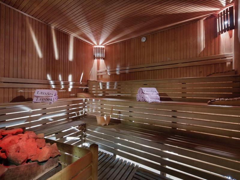 Vnitřní sauna s dřevěnými stěnami, vícestupňovými lavicemi a teplým osvětlením