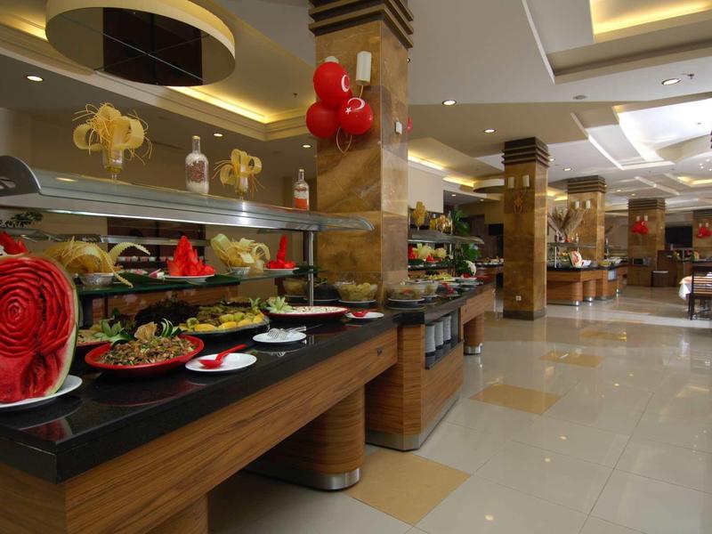 Bufet s různými pokrmy a dekorativním melounem v jasné hotelové restauraci