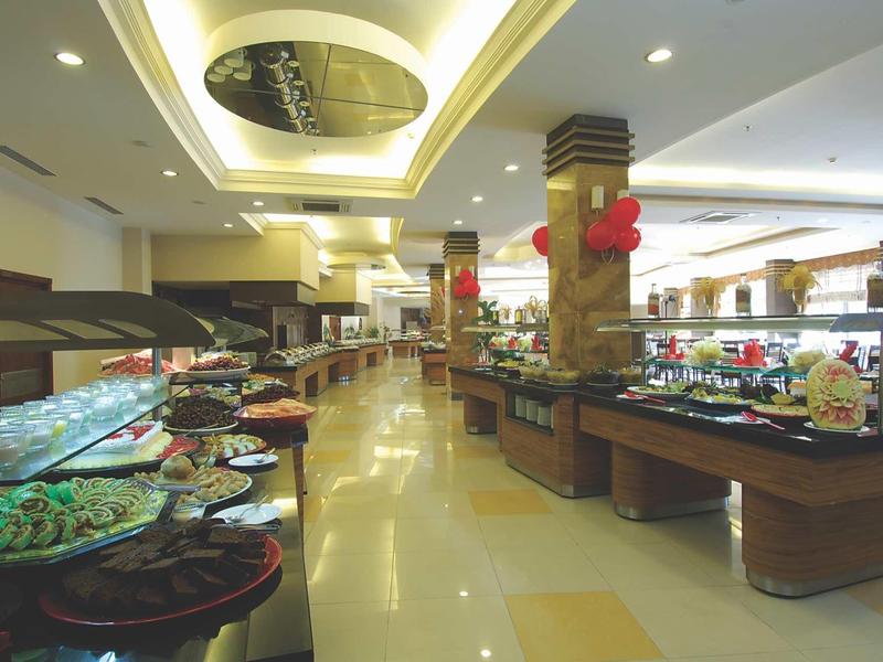 Prostorná hotelová bufetová oblast s rozmanitými pokrmy na dlouhých stolech a moderním designem.