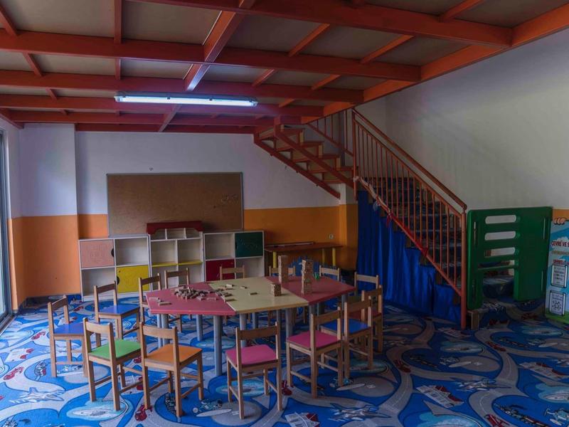 Dětský pokoj s barevnými stoly a židlemi, kobercem a schodištěm v hotelu