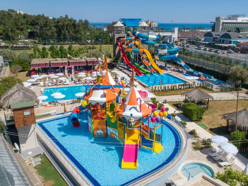 Vodní park s tobogány, vodním hřištěm a několika venkovními bazény za slunečného počasí.