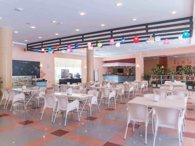 Světla a moderní jídelna s bílými židlemi a barevnými dekoracemi na stropě.