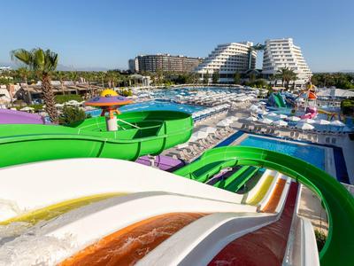Bunte Wasserrutschen in einem großen Poolbereich vor modernen Hotelgebäuden bei klarem Himmel.