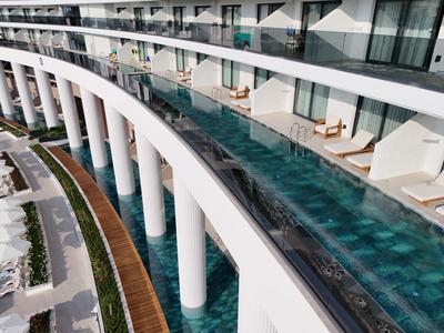 Modern hotel balcony with long narrow pool, white columns, and glass railing.