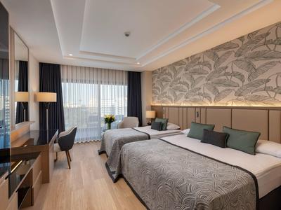 Bright, modern hotel room with two beds, desk, chair, and decorative wall paneling.