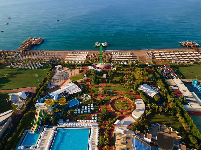 Vista aérea de un gran resort con piscinas, jardines y muelles junto al mar.