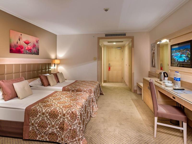 Habitación de hotel acogedora con cama doble, escritorio, silla y ambiente de iluminación cálida.