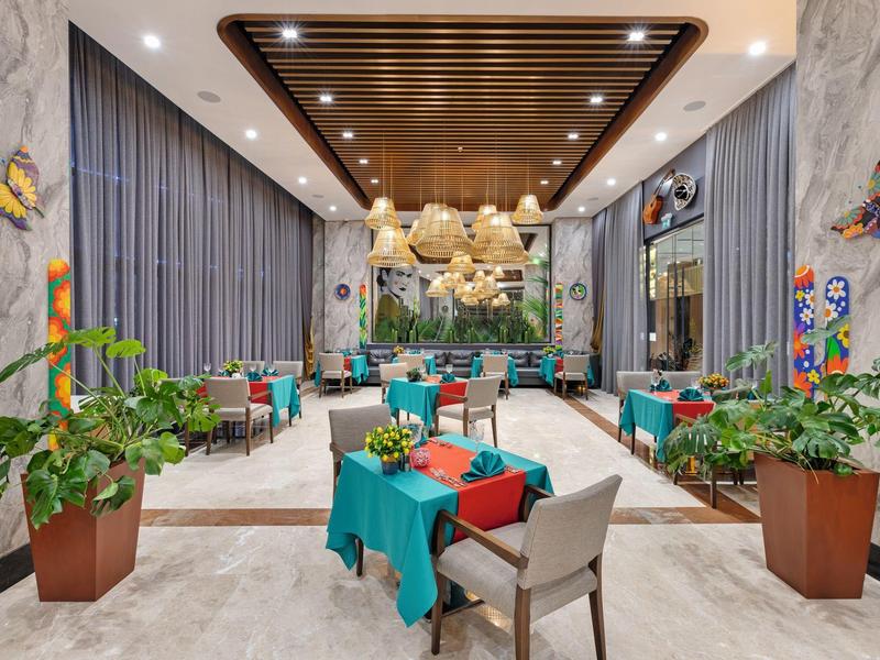 Jardín de hotel moderno con sillas coloridas, plantas y decoración en el techo en ambiente elegante.