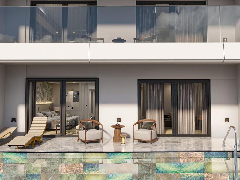 Terraza moderna de hotel con piscina, tumbonas y cómodos sillones frente a dos habitaciones con puertas corredizas de vidrio.