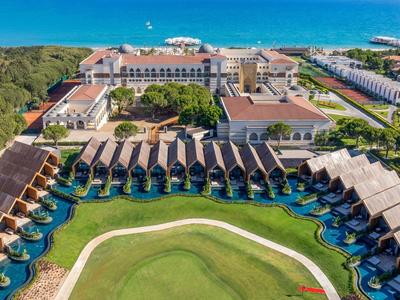 Aerial view of a resort with overwater bungalows, pool, and sea view.