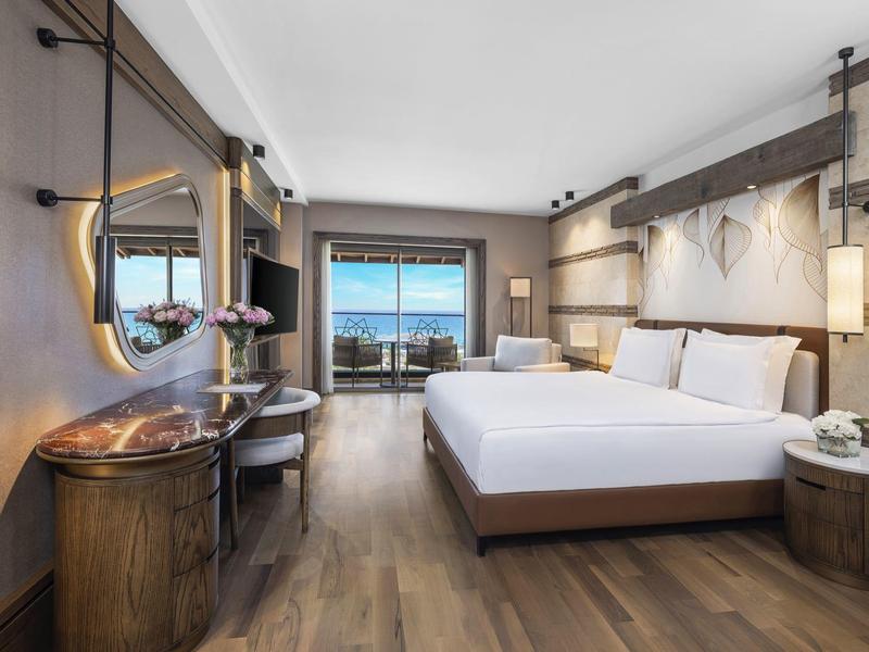 Modern hotel room with double bed, desk, and sea view