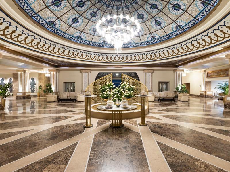 Luxurious hotel lobby with decorative glass ceiling and central floral arrangement