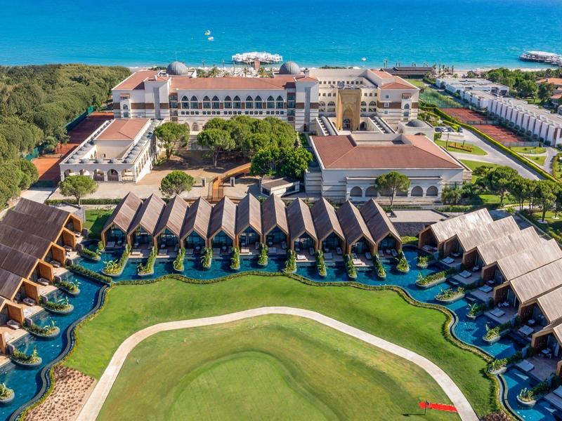 Aerial view of a resort with overwater bungalows, pool, and sea view.