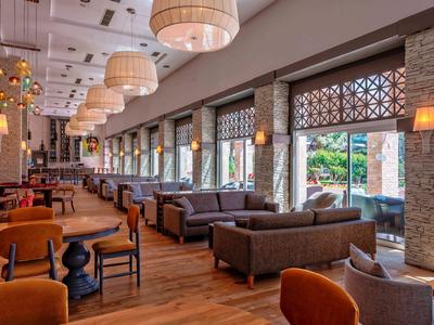 Restaurant d'hôtel lumineux et moderne avec des chaises brunes, des canapés et de grands abat-jours.