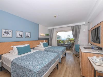 Chambre d'hôtel avec deux lits simples, bureau, balcon et décoration moderne aux couleurs claires.