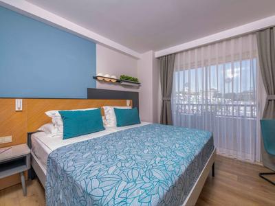 Chambre d'hôtel moderne avec lit double, mur bleu et balcon avec vue extérieure