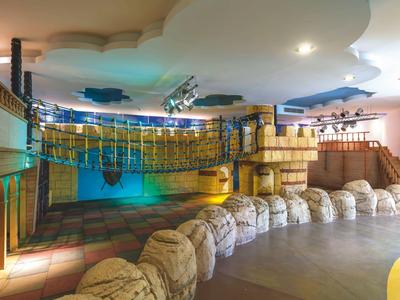 Grand espace intérieur avec poutres en bois, canapés et lumières colorées dans une zone de jeu d'hôtel.