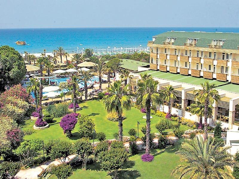 Grand complexe hôtelier avec jardins luxuriants et vue sur la mer à l'arrière-plan.