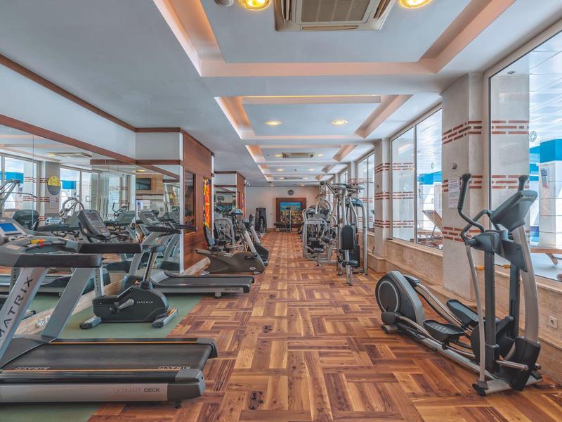 Salle de sport d'hôtel lumineuse avec équipement cardio moderne et sol en bois