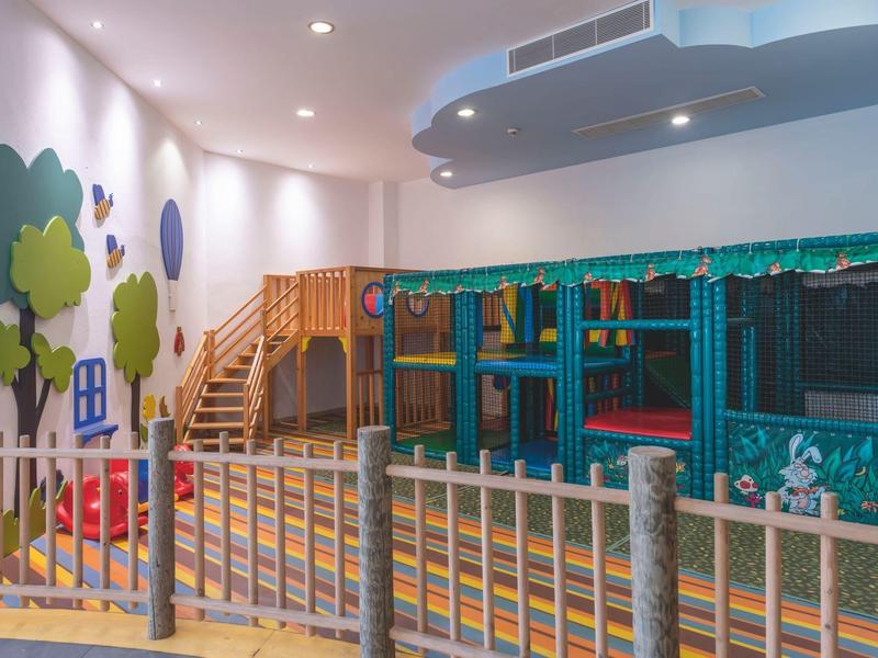 Espace de jeux pour enfants dans un hôtel avec des structures d'escalade souples et des murs peints.