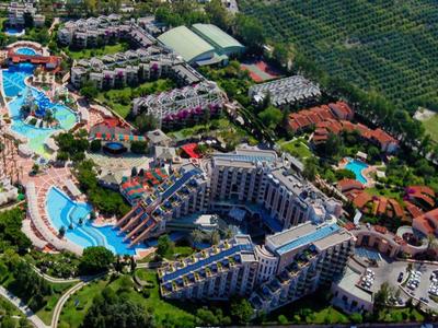 Veduta aerea di un grande resort sulla spiaggia con più piscine, edifici e accesso diretto al mare.