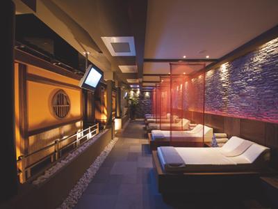 Luxe spa met ligstoelen, warme verlichting en een stenen wanddecoratie.