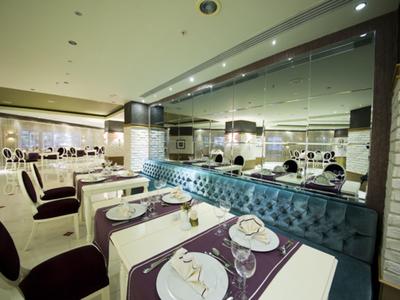 Modern restaurant met paarse stoelen, witte tafels met borden en blauw getuft bankje.