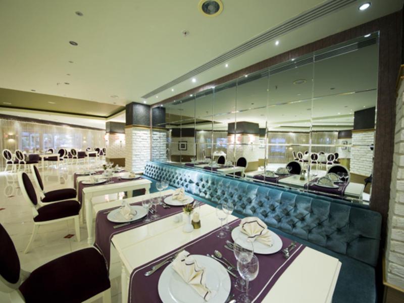 Modern restaurant met paarse stoelen, witte tafels met borden en blauw getuft bankje.