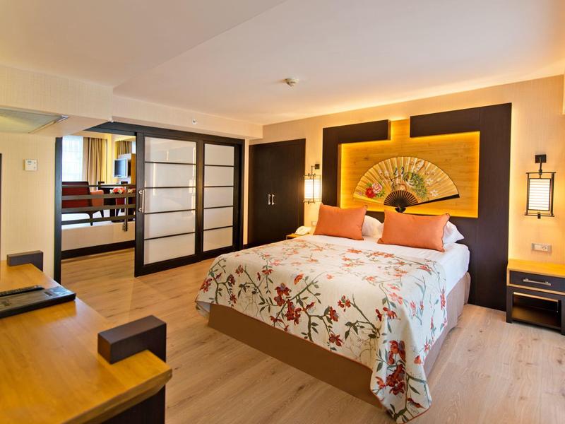 Lichte hotelkamer met bloemrijk bedsprei, houten meubels en Japanse schuifdeuren.