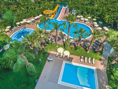 Großer Poolbereich mit Wasserrutschen, Palmen und Liegestühlen in einem tropischen Resort.
