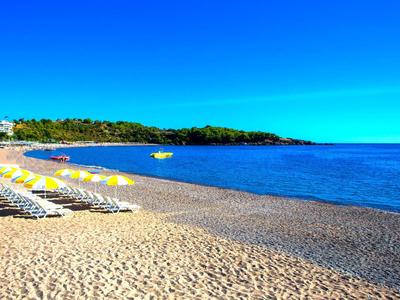 Zandstrand met ligbedden en blauwe lucht bij rustige zee