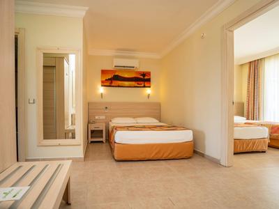 Hell eingerichtetes Schlafzimmer mit Doppelbett, Nachttischen, Spiegel und großer Fensterfront.