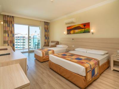 Modernes Hotelzimmer mit zwei Betten, Balkon, Sitzbereich und hellem Holzmöbel-Interieur.