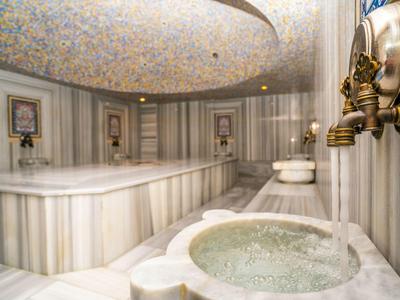 Luxuriöser türkischer Hamam mit Marmorkacheln, verziertem Deckenmosaik und Wasserquellen.