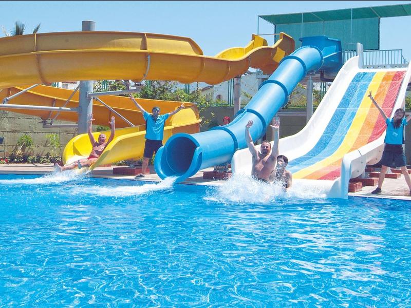 Bunte Wasserrutschen führen ins klare blaue Schwimmbecken eines Aquaparks bei Sonnenschein.